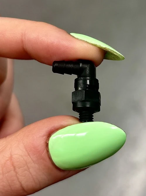 Miniature swivel elbow nylon fitting held between index finger and thumb