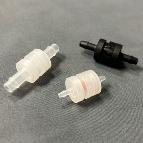 Two translucent and one black umbrella check valves on a cloth gray background